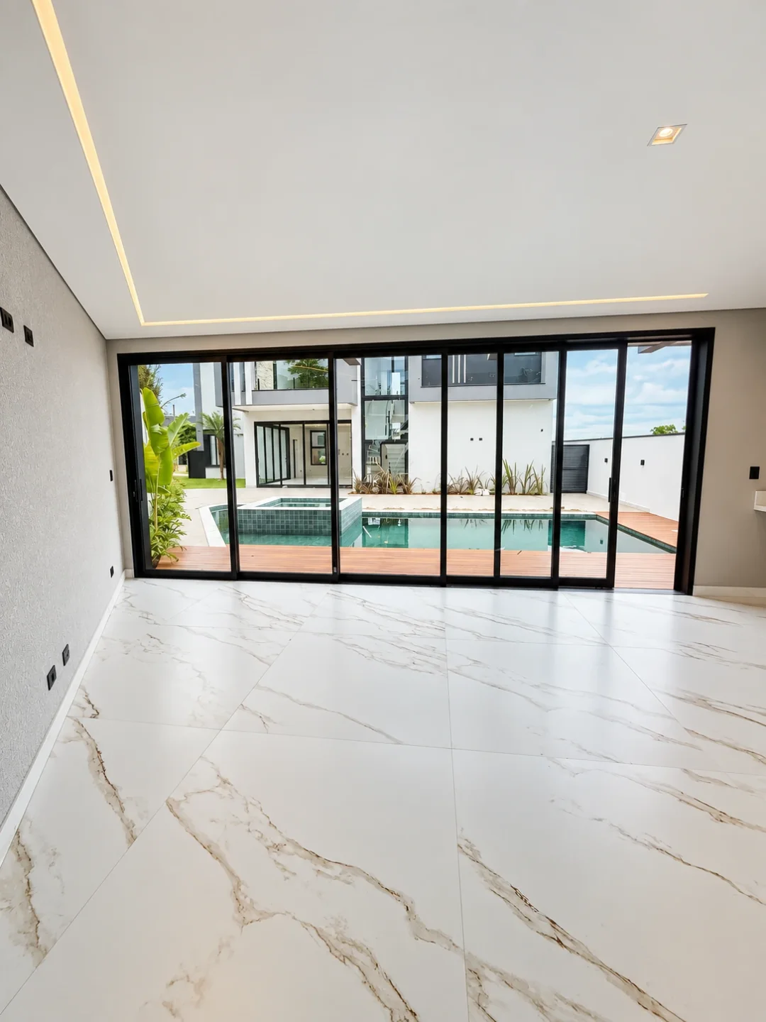 Sala com portas de vidro voltadas à piscina no Aruã Brisas, em Mogi das Cruzes — Ref. 0087