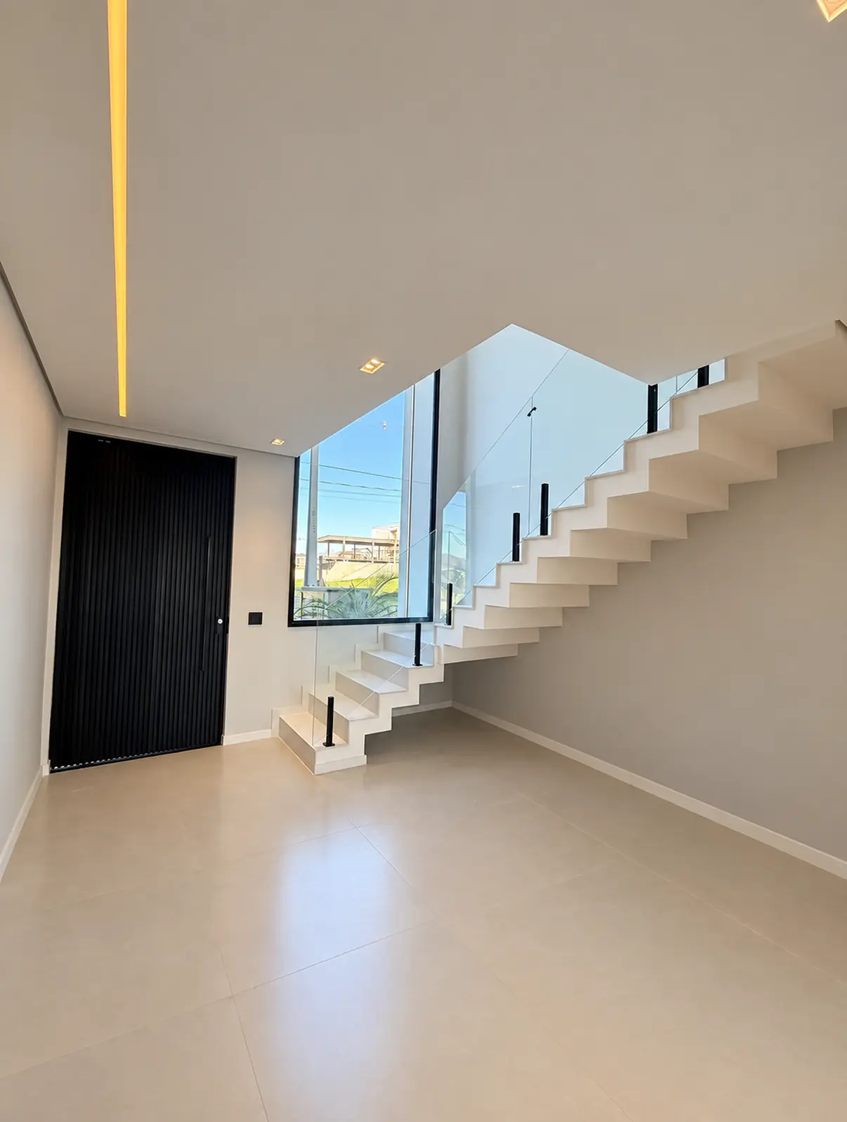Sala de entrada com escada e guarda-corpo de vidro