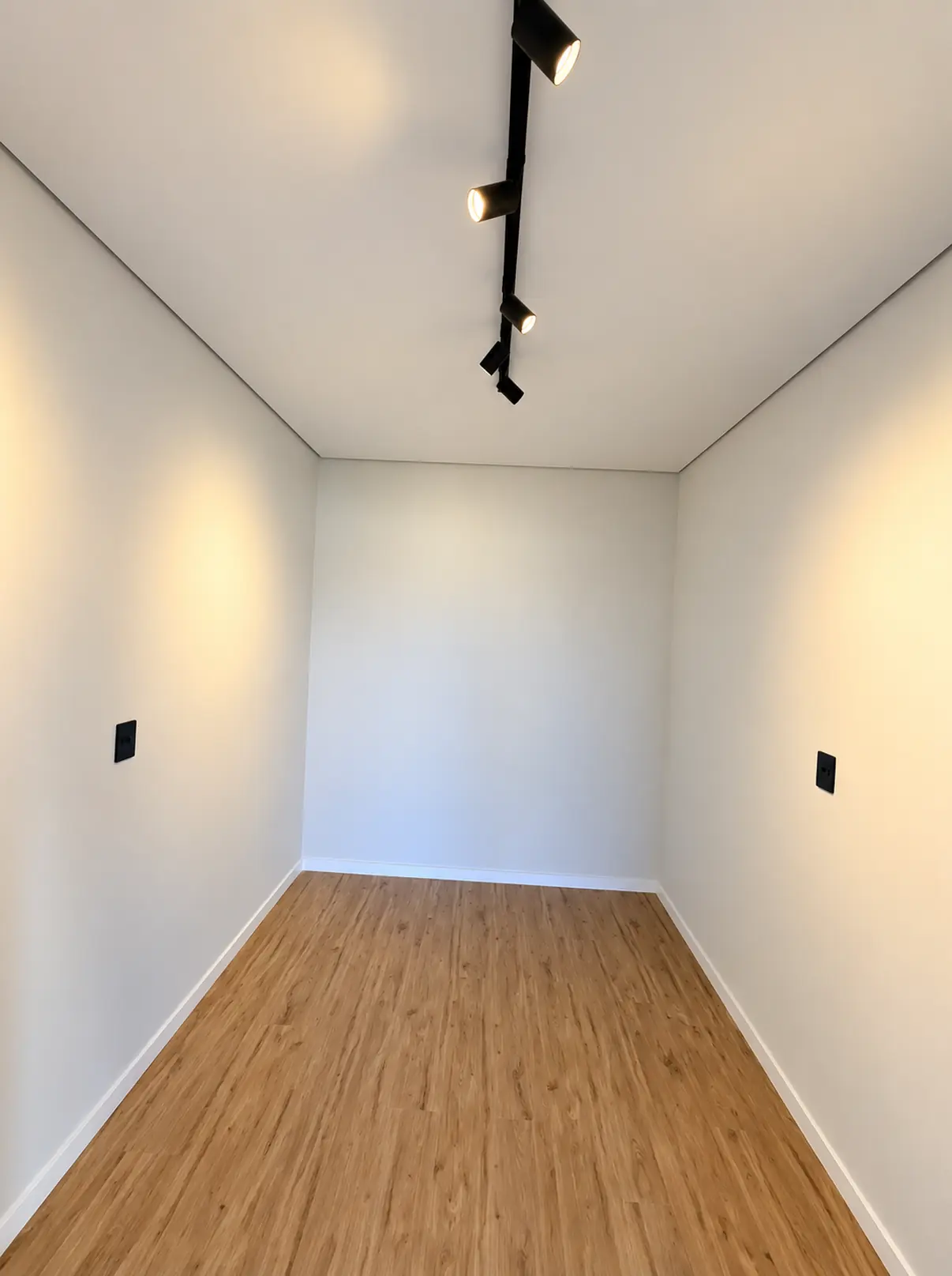 Ambiente com piso amadeirado e trilho de iluminação