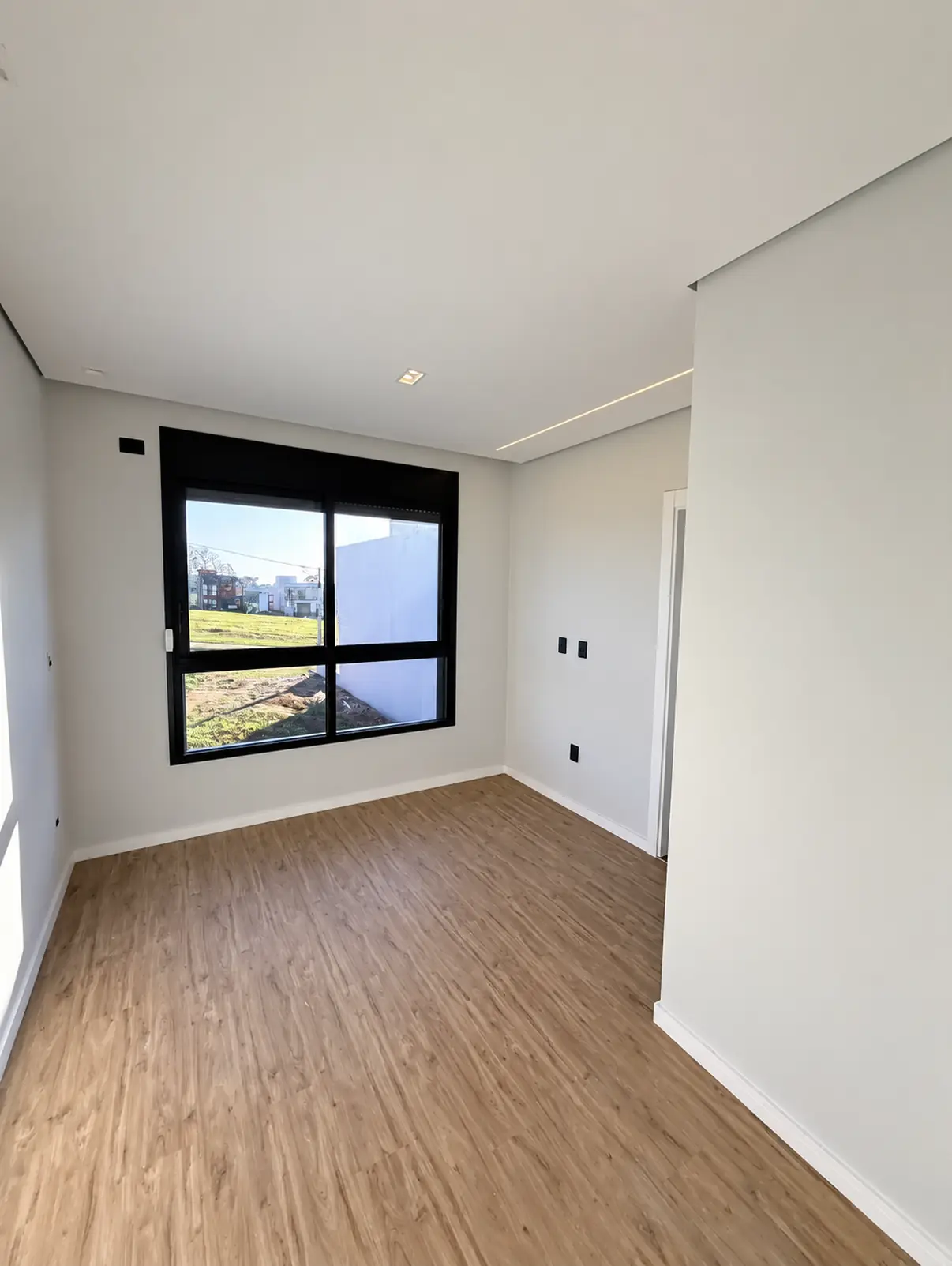 Dormitório com piso amadeirado e janela