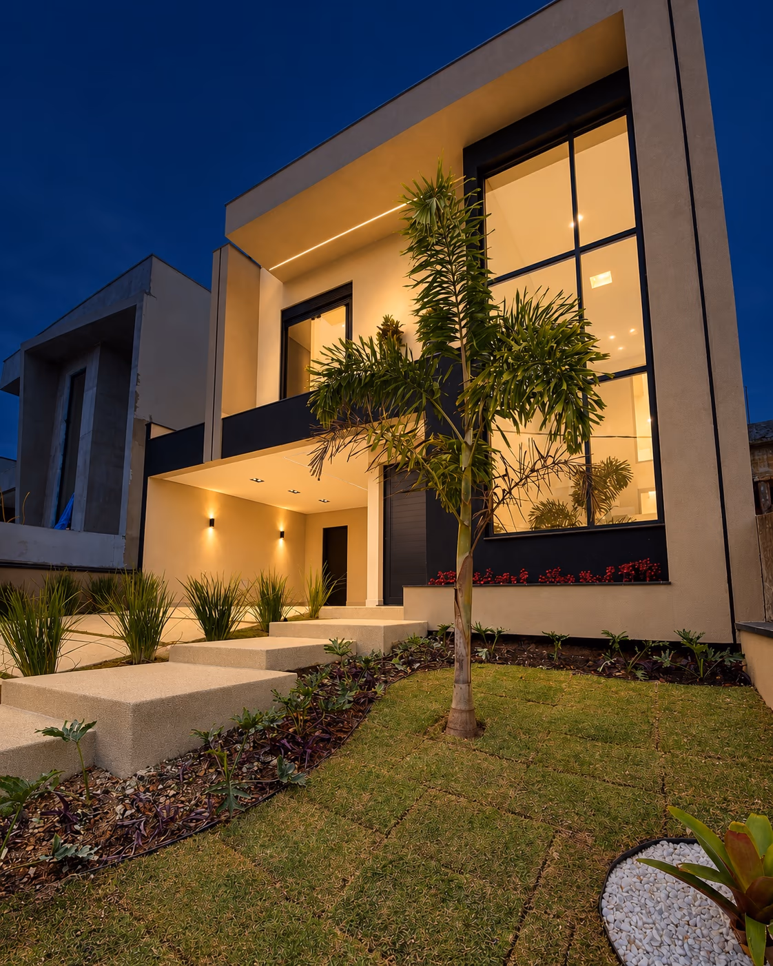 Fachada contemporânea da casa no Mosaico Horizontes, com jardim e iluminação acesa — Mogi das Cruzes, Ref. 0111.