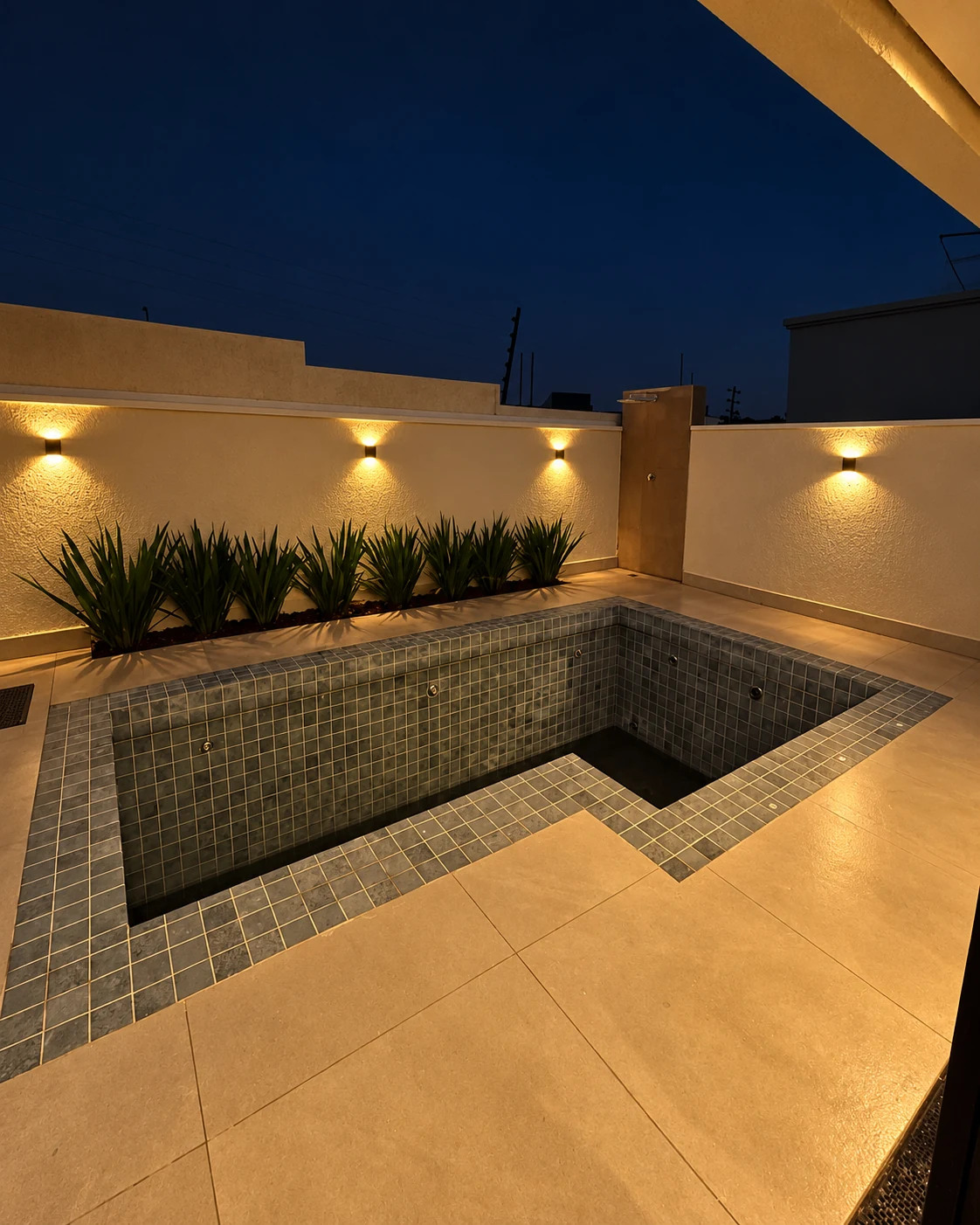 Piscina com banco interno, jardim lateral e ducha externa — iluminação noturna editada