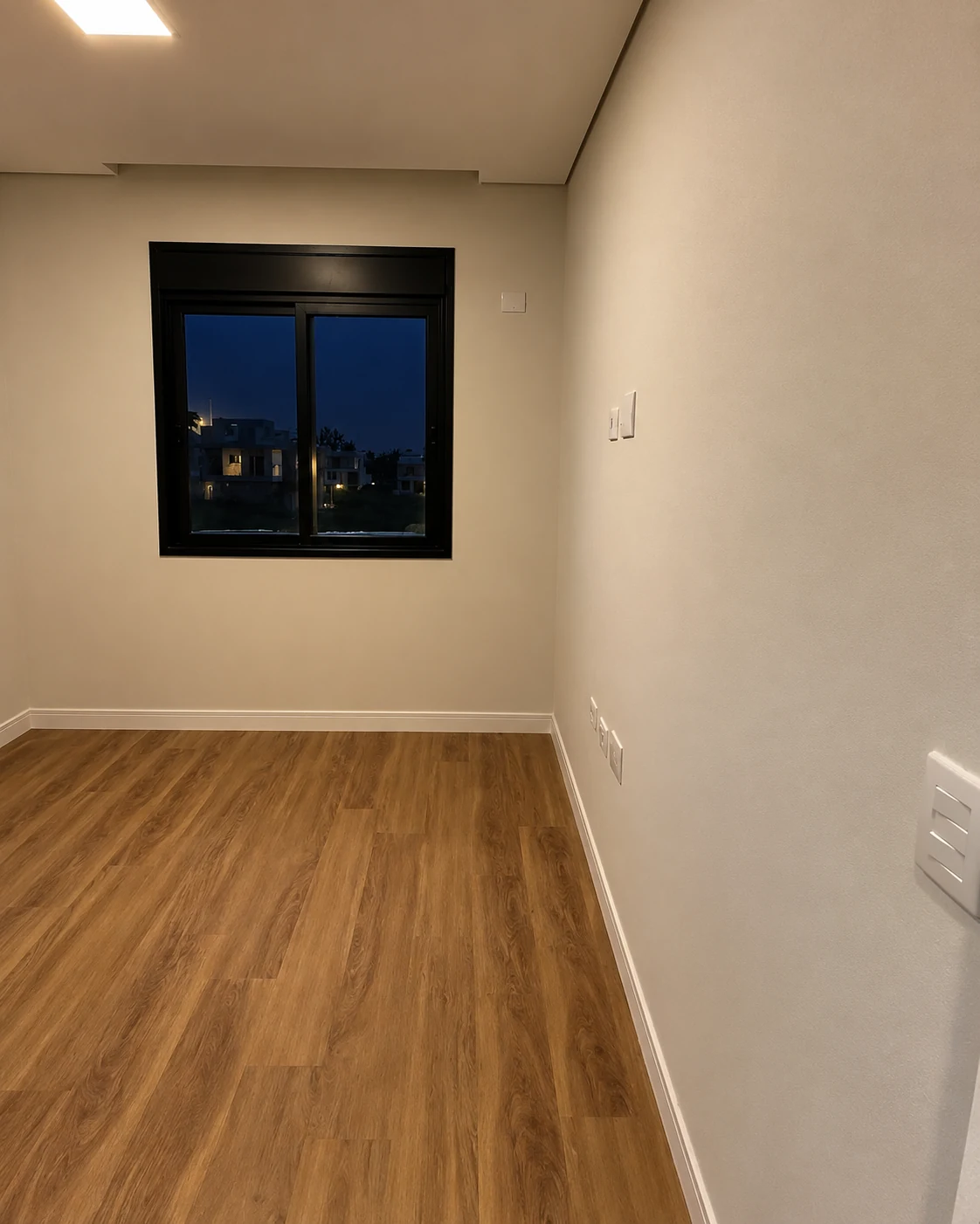 Dormitório com janela de esquadria escura — iluminação noturna editada