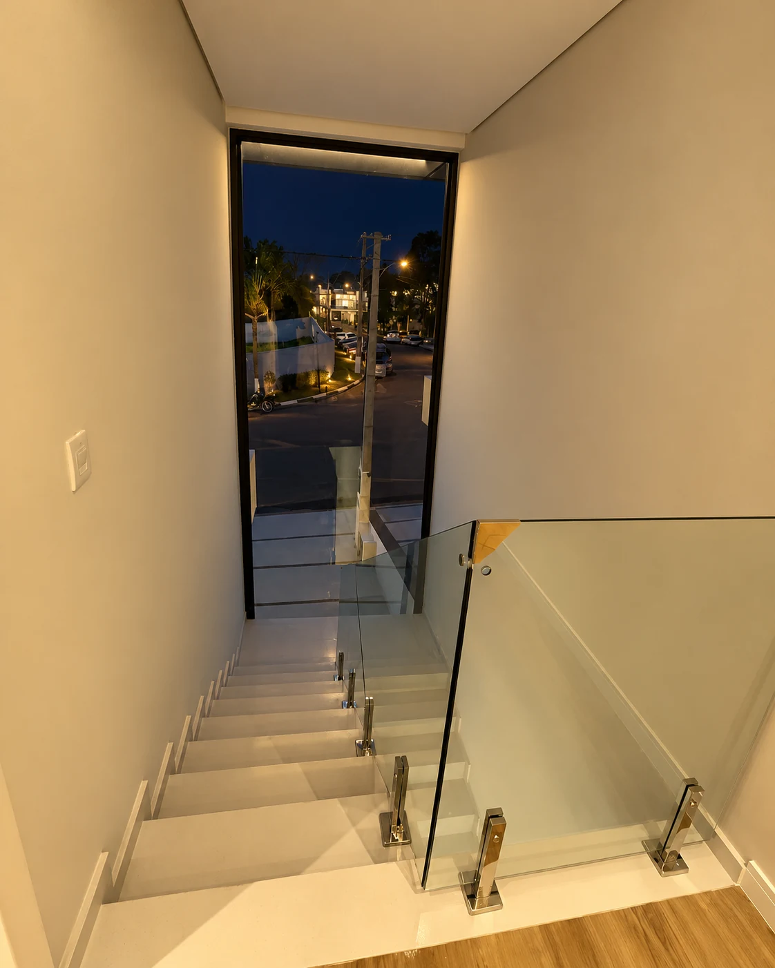 Escada vista do pavimento superior com guarda-corpo de vidro — iluminação noturna editada