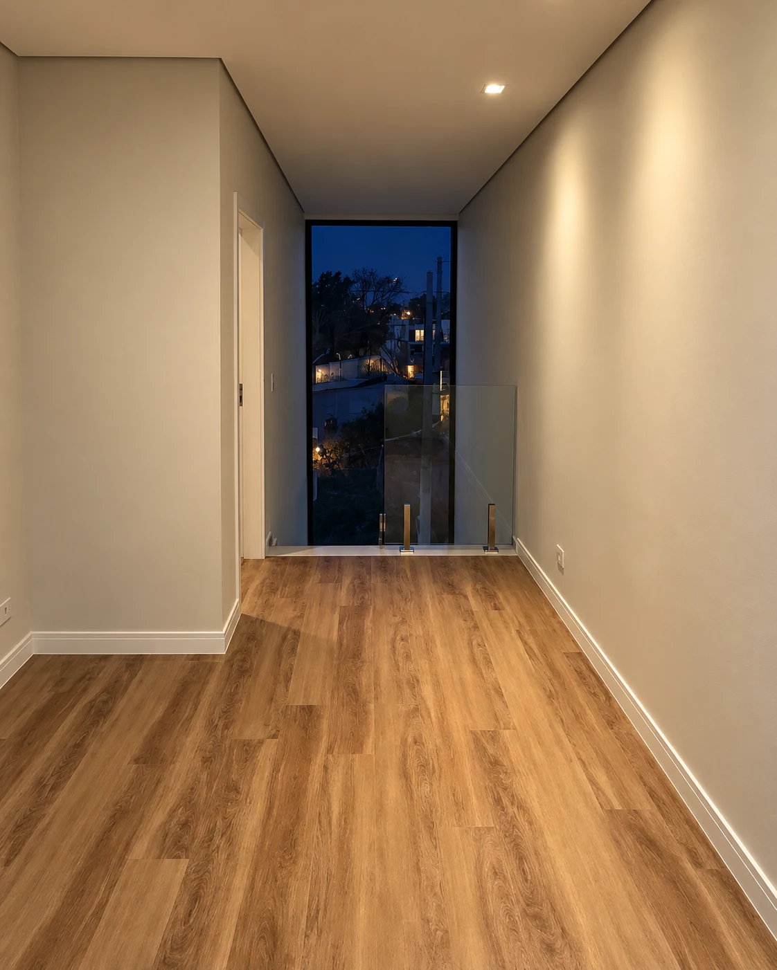 Circulação superior com piso de aparência amadeirada e janela vertical — iluminação noturna editada